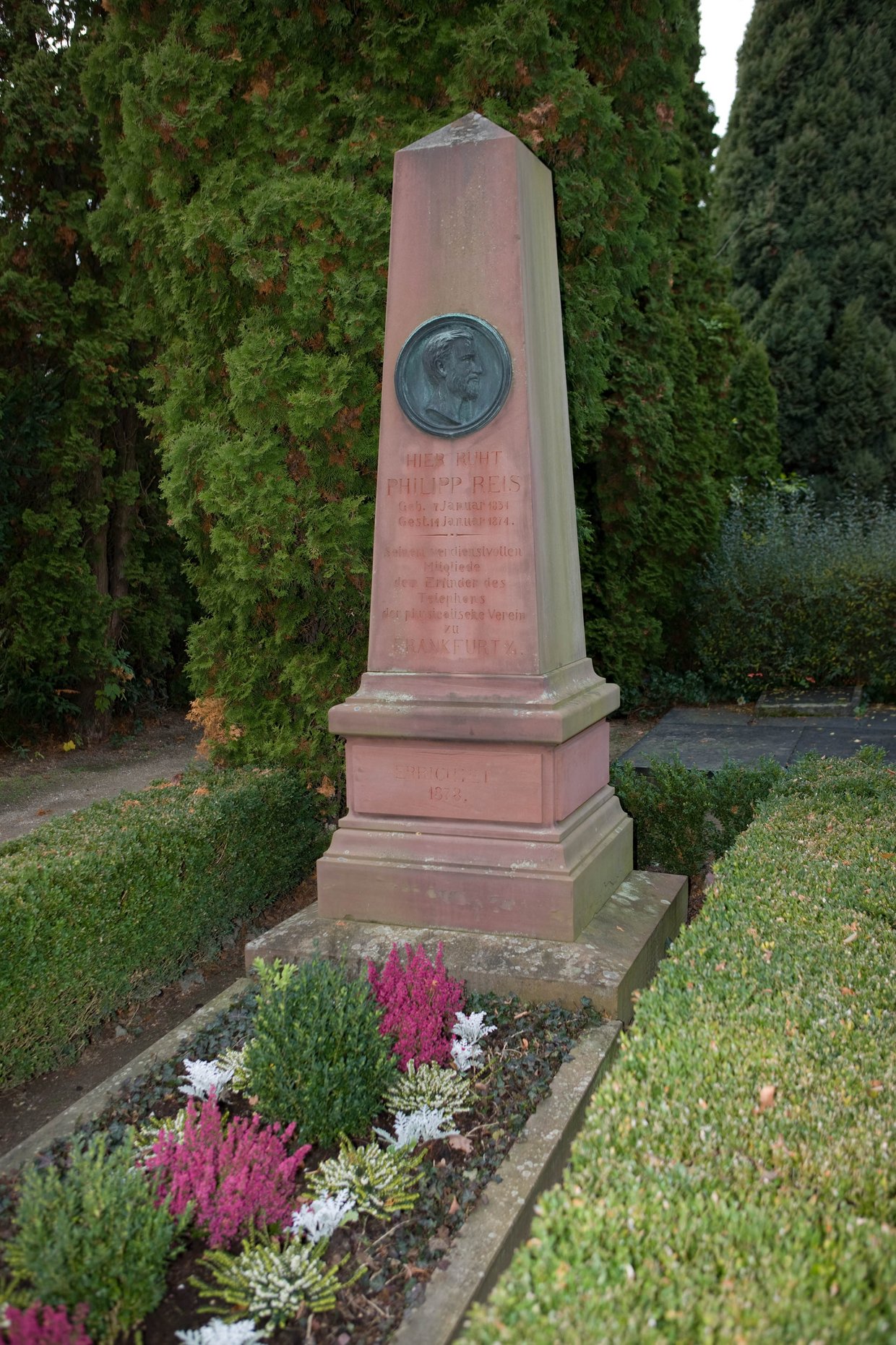 Auf der Darstellung ist die Grabsäule aus rotem Sandstein auf dem Grab von Philipp Reis zu sehen.