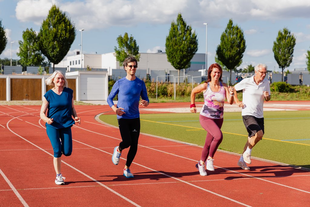 Auf dem Bild rennen vier Menschen auf der Laufbahn des Sportparks.