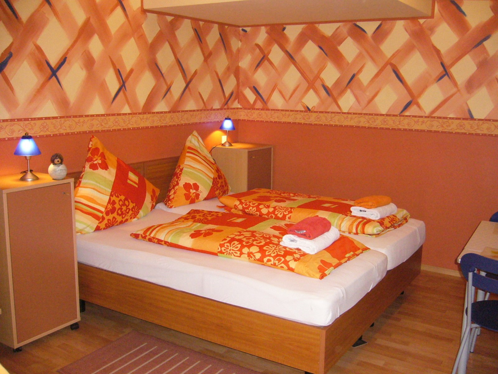 Auf der Darstellung ist ein Zimmer mit Doppelbett zu sehen.