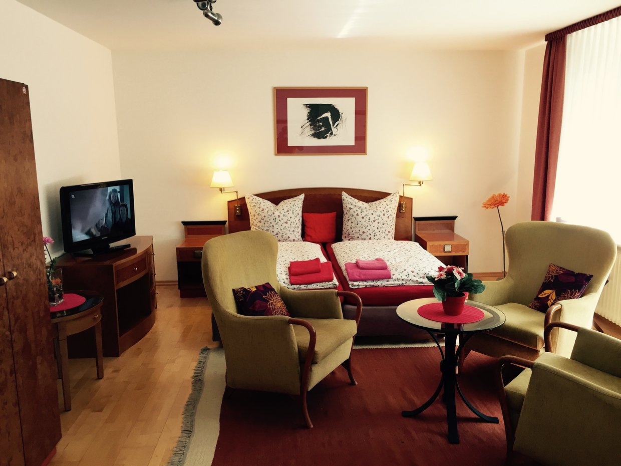 Auf der Darstellung ist das Ferienappartement Hofmann mit Doppelbett und Sitzmöbeln zu sehen.