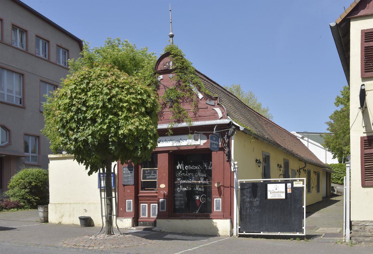 Auf der Darstellung ist ein kleines Färbhäuschen mit verziertem Giebel zu sehen, das heute ein Bistro beherbergt.