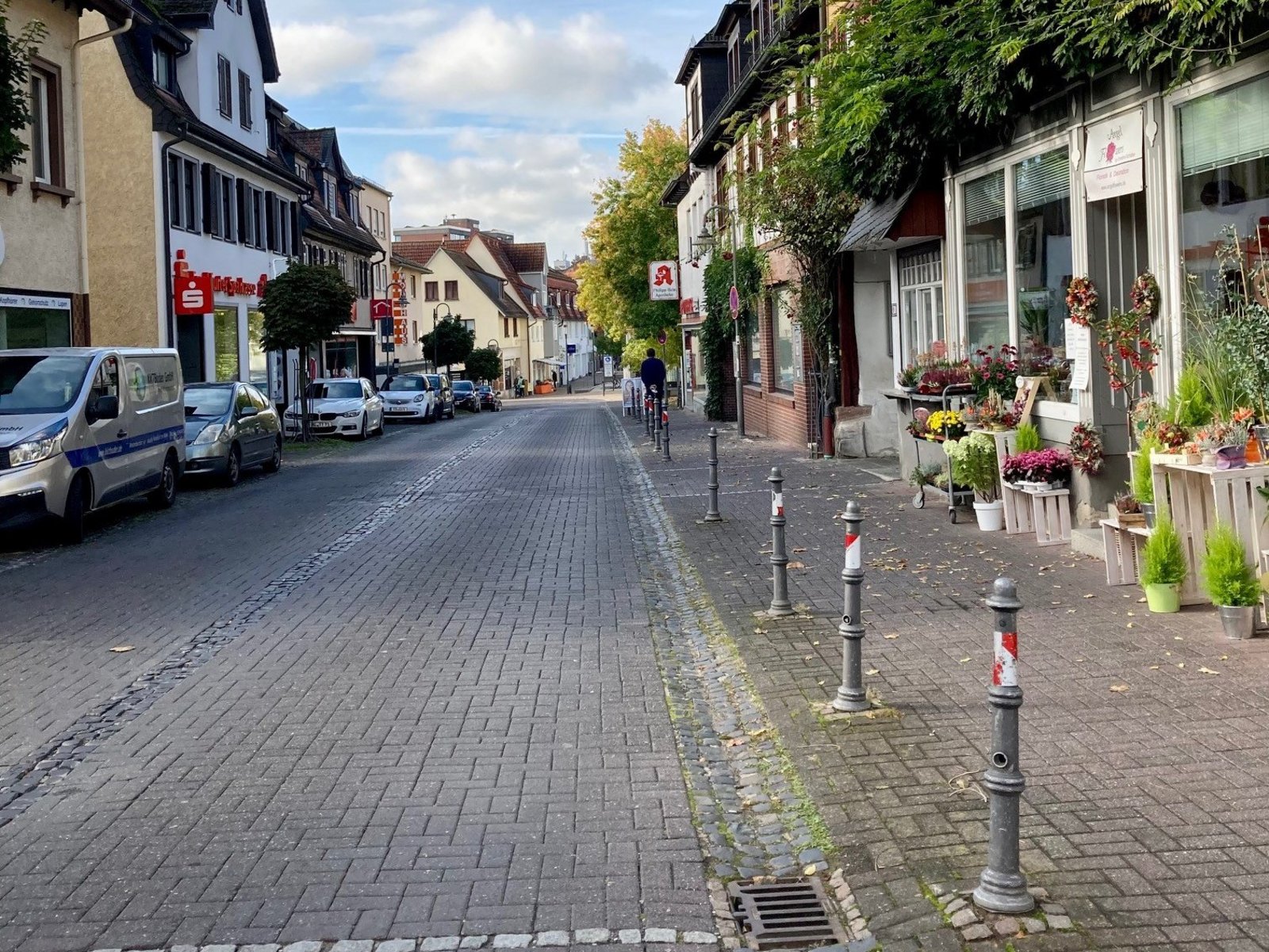 : Zu sehen ist eine Einzelhandelsstraße mit einem Blumengeschäft.