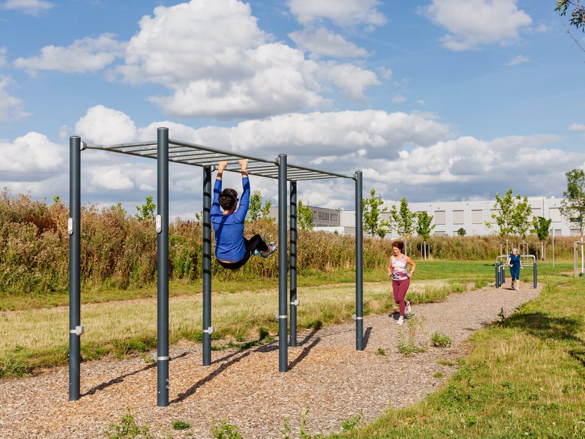 Das Bild zeigt Menschen, die den Hindernispfad nutzen. Sie hangeln sich zum Beispiel an einem Gerüst entlang.