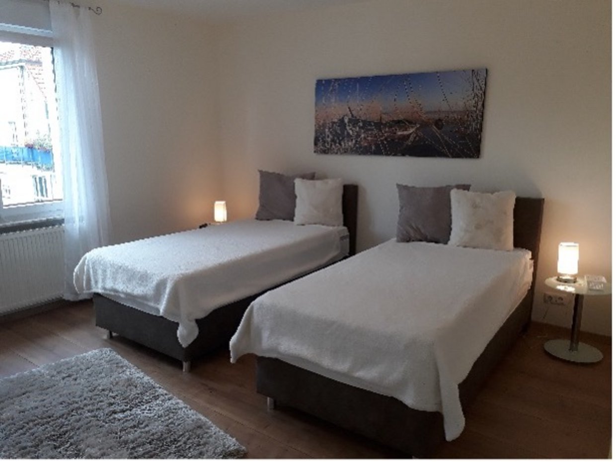 Auf der Darstellung ist das Schlafzimmer der Ferienwohnung mit zwei Einzelbetten zu sehen.