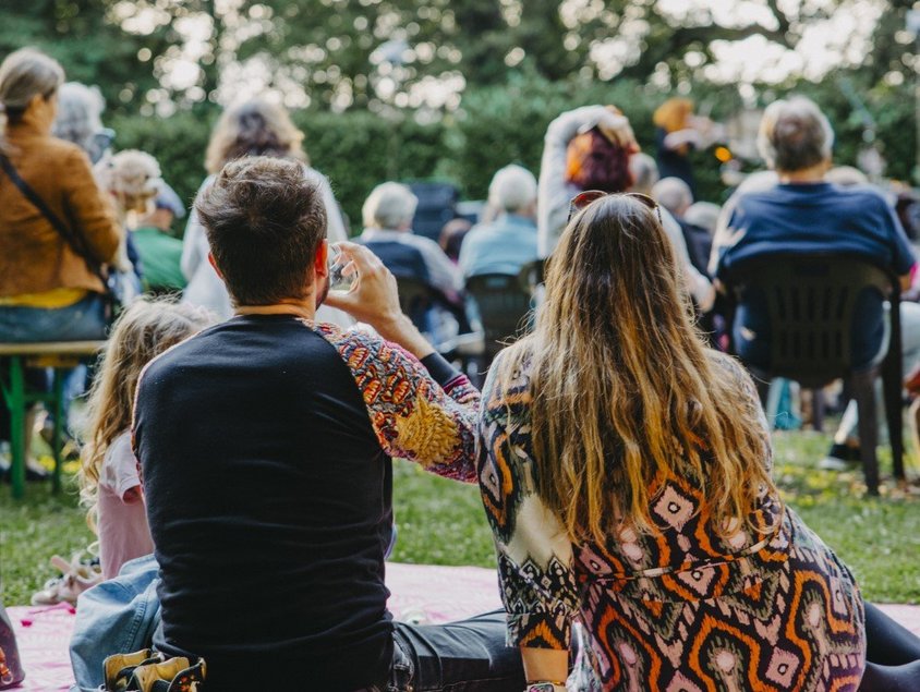 Eine Familie sitzt auf einer Decke und schaut zur Bühne.