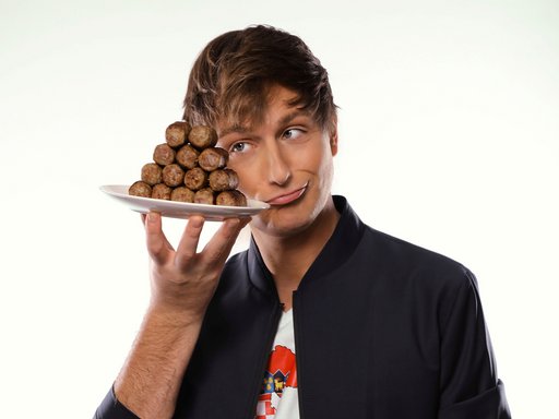 Auf dem Bild ist Comedian Boris Stijelja zu sehen, der eine Platte Cevapcici in der Hand hält..