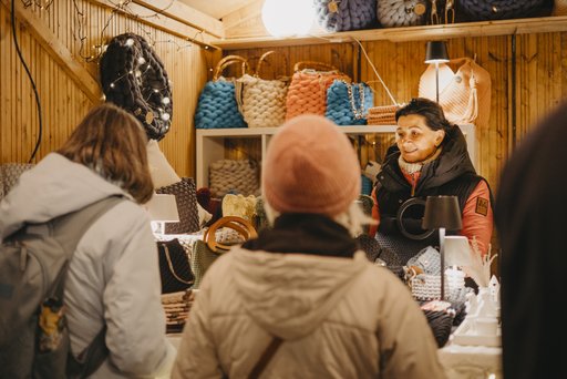 Eine Frau die an einem Stand mit Kunden spricht.
