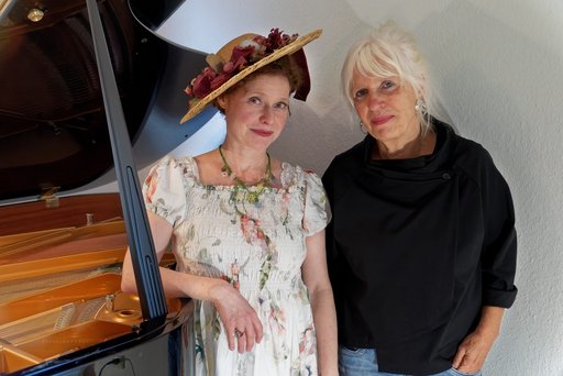 Auf dem Bild sind Jenny Rehs in romantischem Blumenkleid und Hut gekleidet und Pianistin Waltraut Bartl zu sehen.