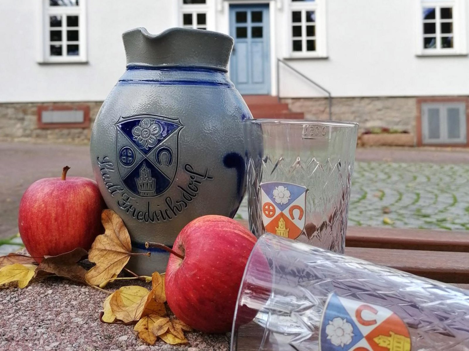 Auf der Darstellung ist ein Bembel mit zwei gerippten Gläsern jeweils mit dem Stadtwappen zu sehen.