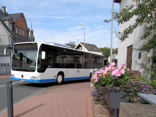 Auf dem Bild ist ein Bus in Friedrichsdorf zu sehen, wie er an einer Straßenkreuzung abbiegt.