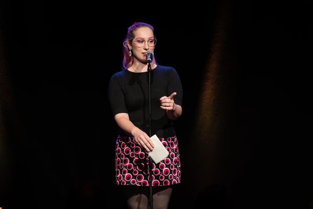 Friedrichsdorfer Poetry Slam Moderation Auf dem Bild ist Katharina Marosz mit einem Mikrofon zu sehen.