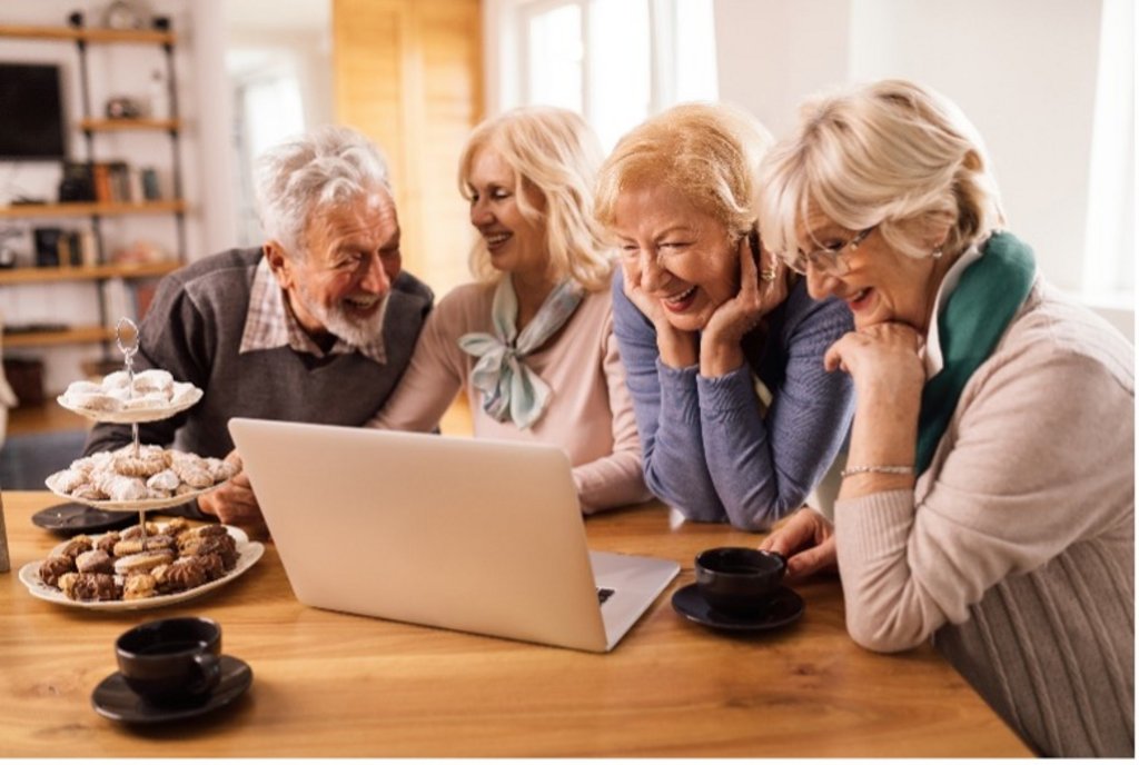 Das Bild zeigt vier Senioren, die gemeinsam im Internet surfen.