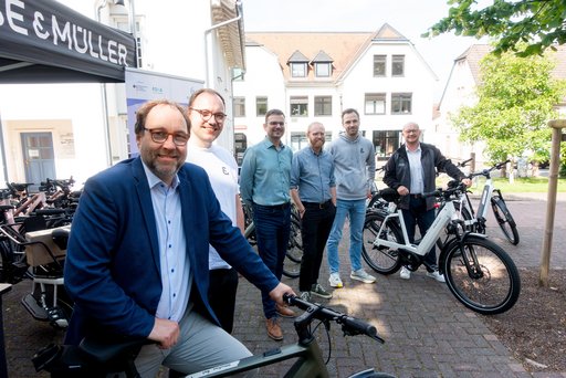 Das Bild zeigt die Übergabe von E-Bikes im Rahmen des Pendelexperiments 2025. Zu sehen sind unter anderem Bürgermeister Lars Keitel, Mobilitätsmanager Sven Wingerter, Mobilitätsforscher Dr. Luca Nitschke und Rouven Kötter. Mehrere E-Bikes sind im Bild zu sehen.